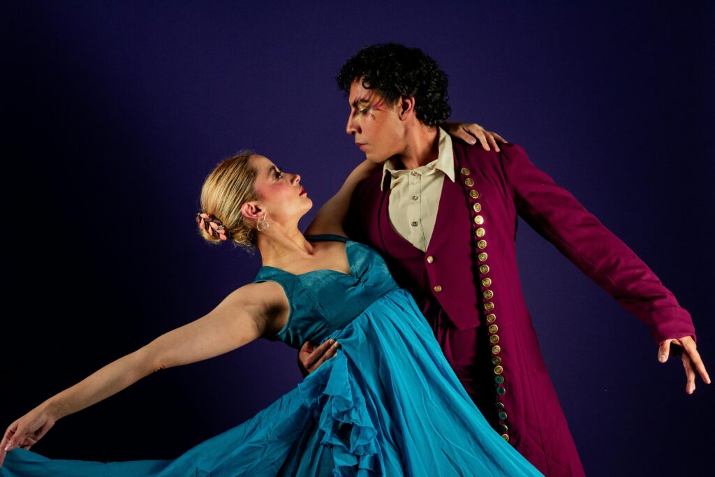 A dramatic studio photograph of a couple performing a flamenco dance in vibrant costumes.